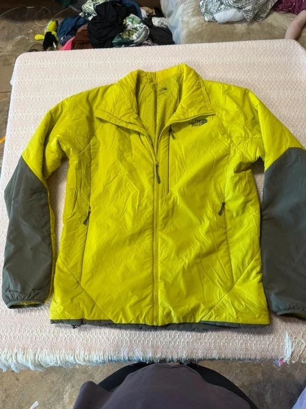 Men's North Face coat in yellow-green with dark sleeves, laid flat